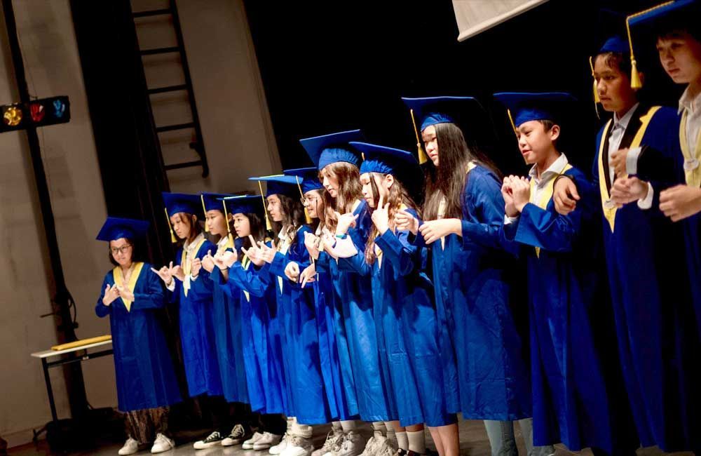 A group of children in graduation caps and gowns are standing on a stage.
