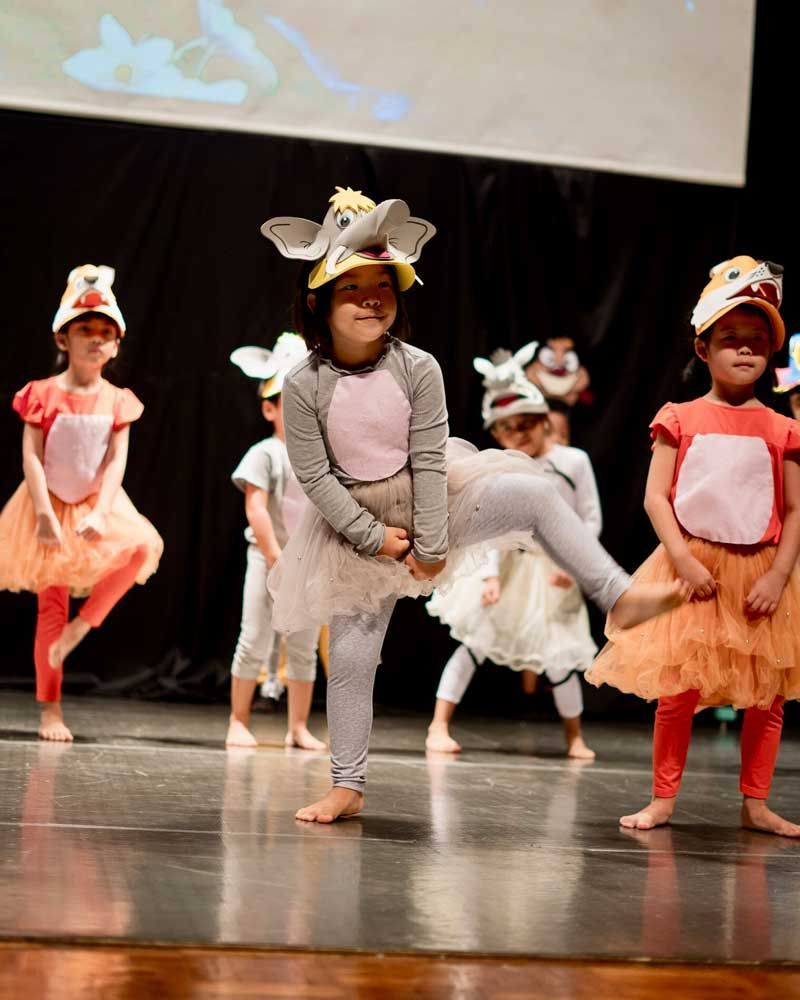 A group of young girls are dancing on a stage.