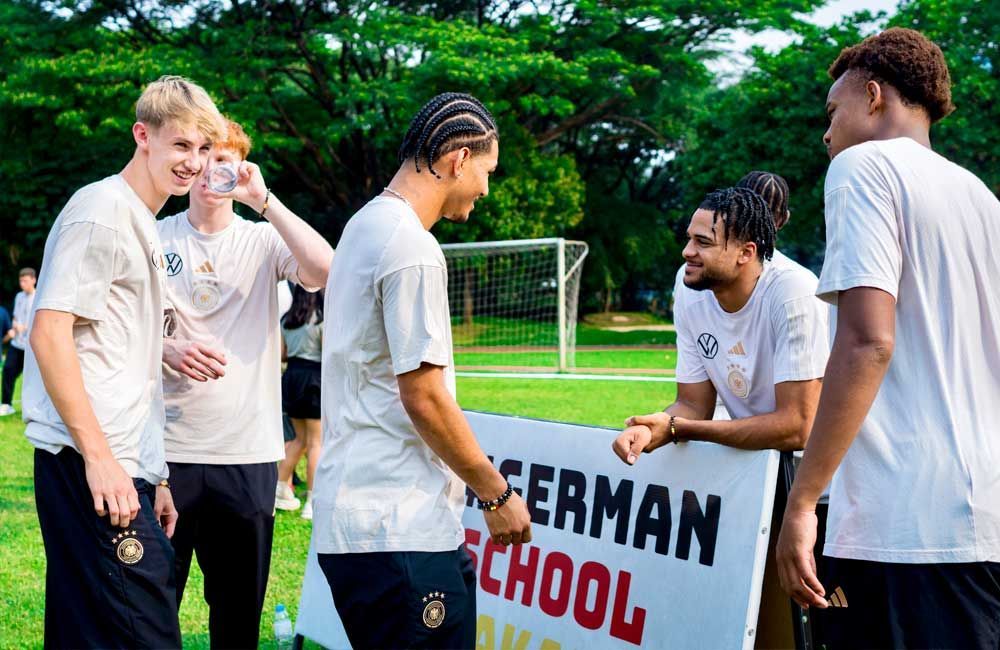 A group of young men are standing around a sign that says german school.