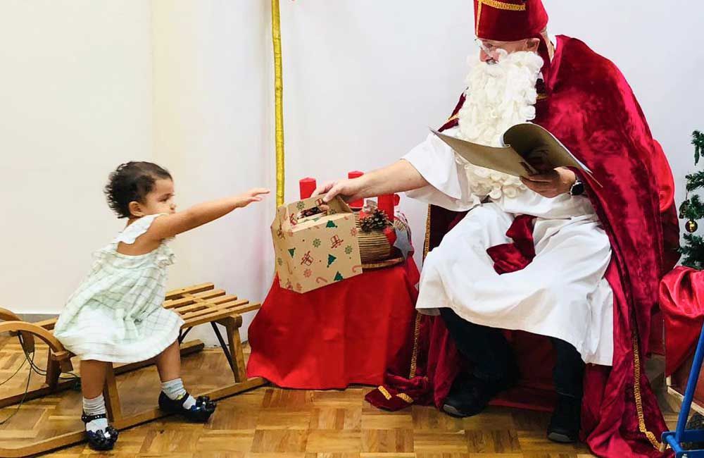 A little girl is standing next to a man dressed as santa claus.