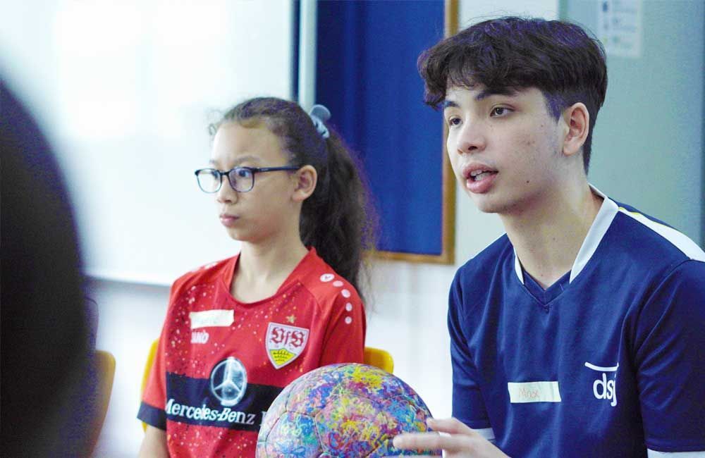 A boy and a girl are sitting in a classroom holding a globe.
