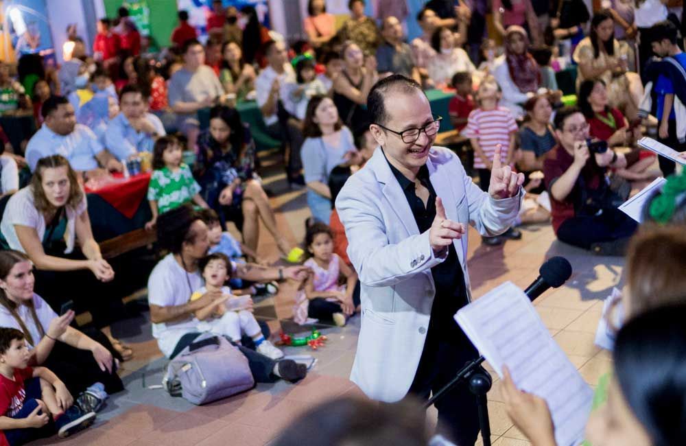 A man is singing into a microphone in front of a crowd of people.