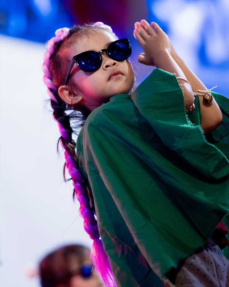 A little girl wearing sunglasses and a green shirt