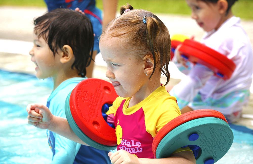 A boy and a girl are playing in a swimming pool