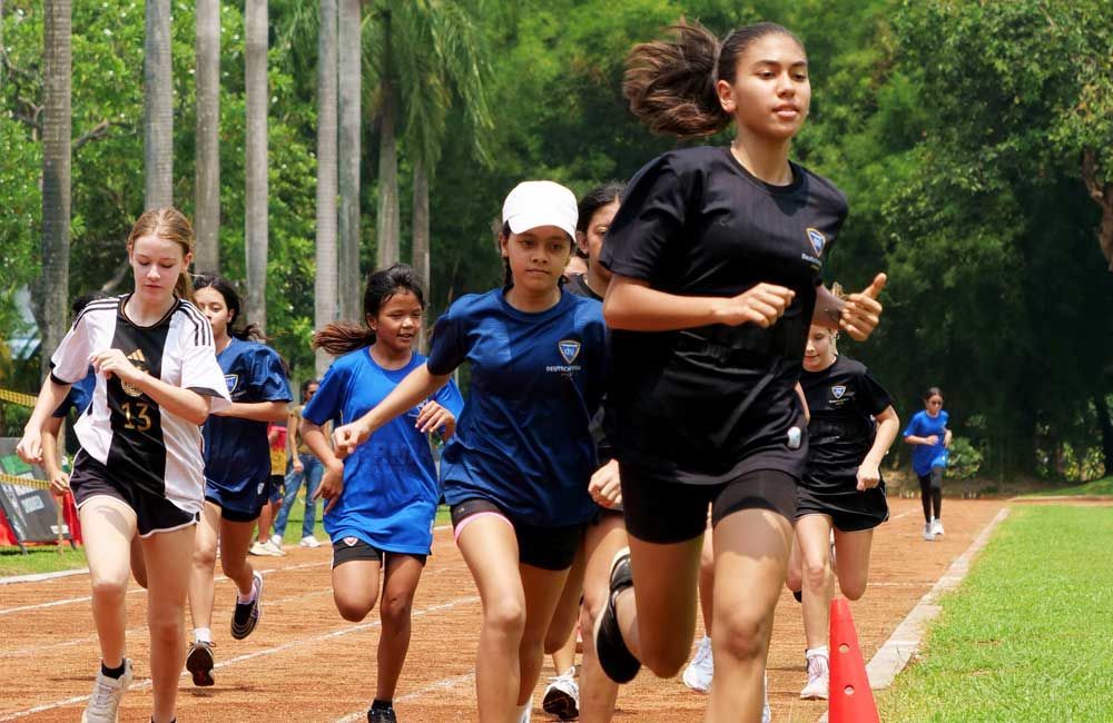 A group of young girls are running on a track.