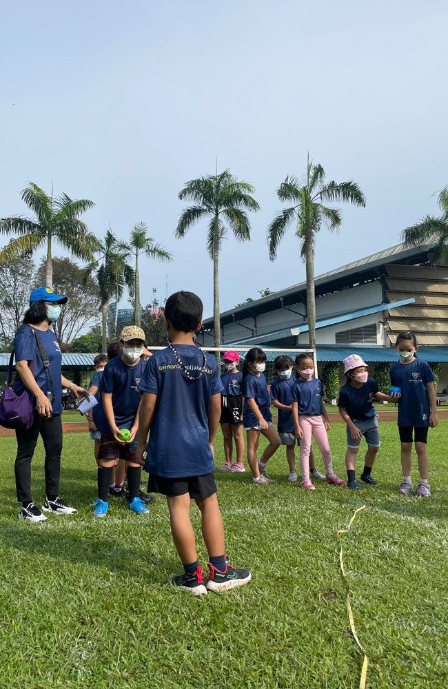 A group of children are standing on top of a lush green field.
