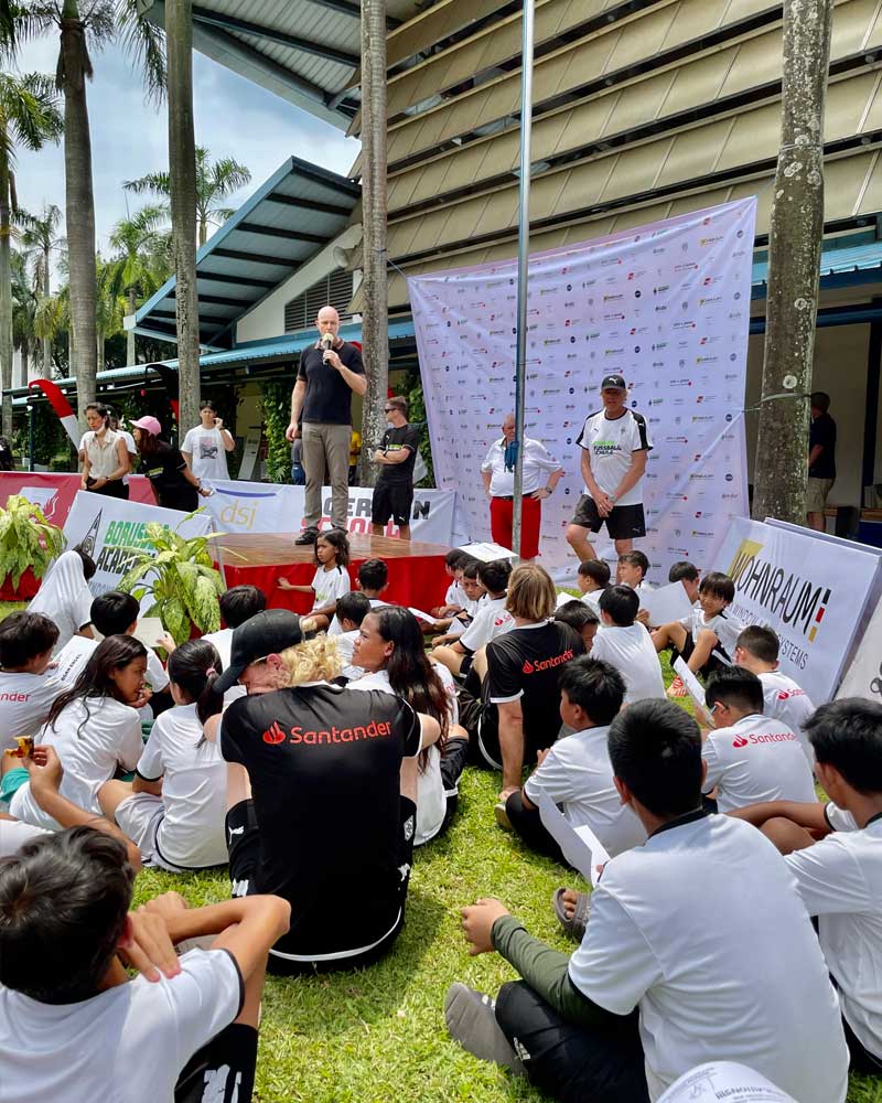 A group of people are sitting on the grass in front of a stage.