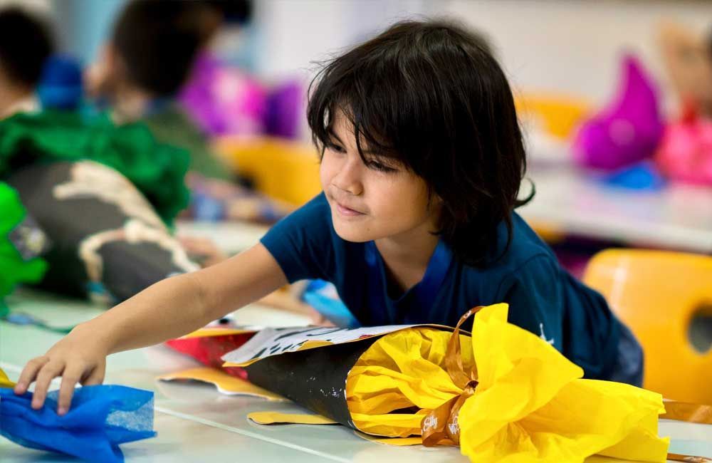 A young boy is playing with tissue paper in a classroom.