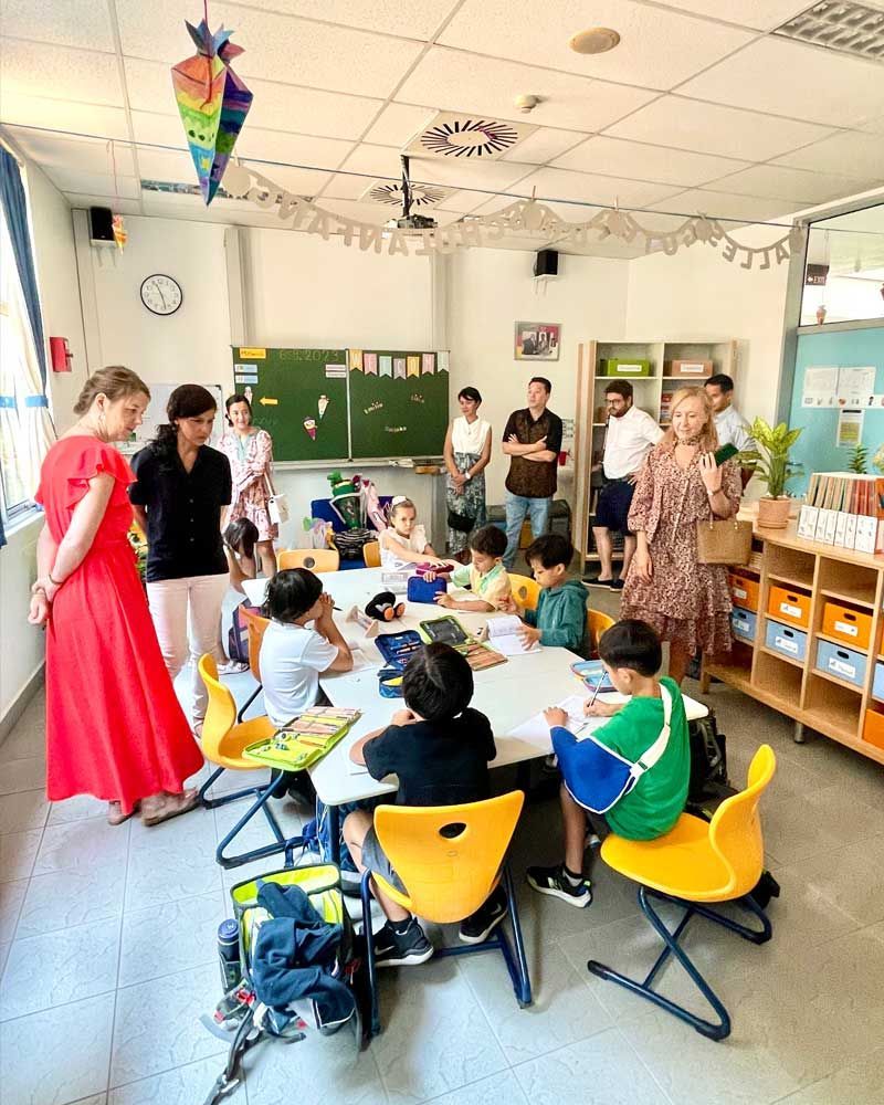 A group of children are sitting around a table in a classroom.