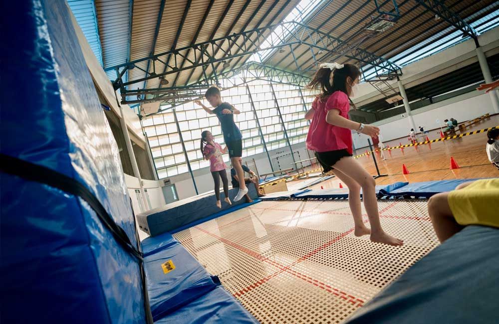 A group of children are jumping on a trampoline in a gym.
