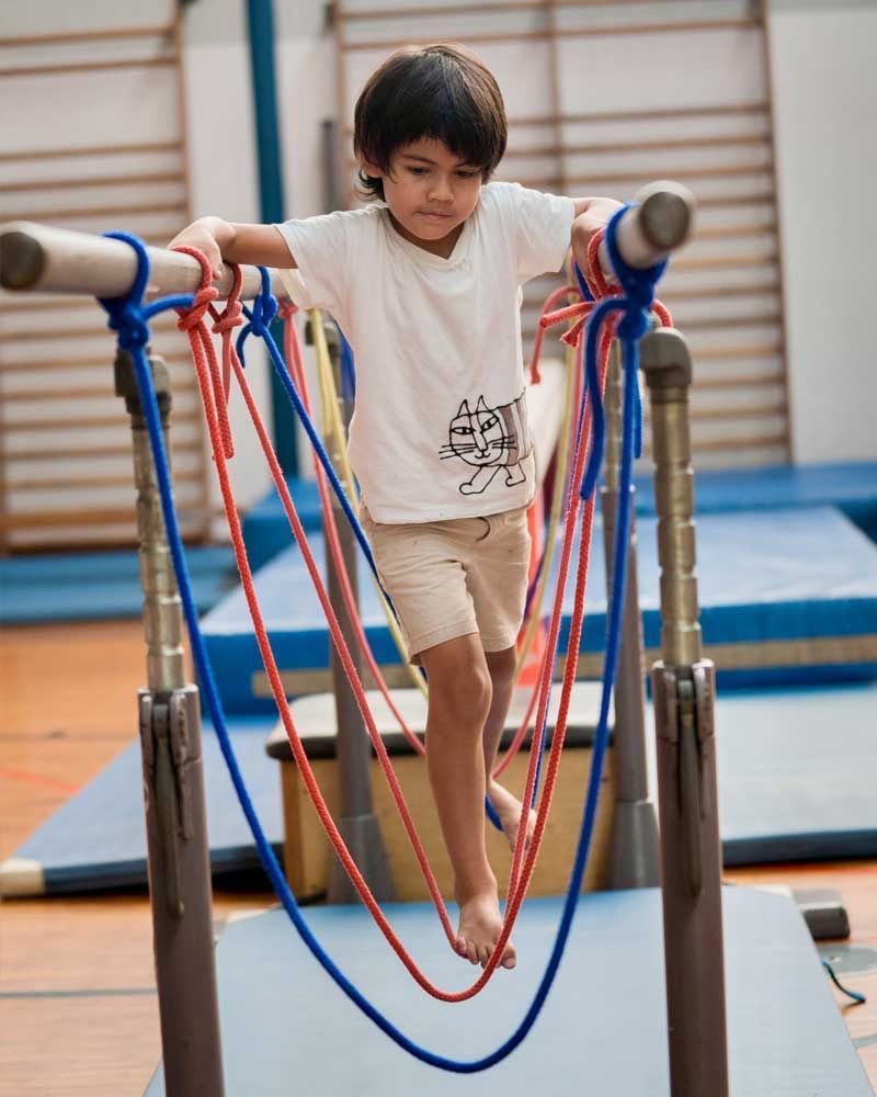 A young boy is playing with ropes in a gym