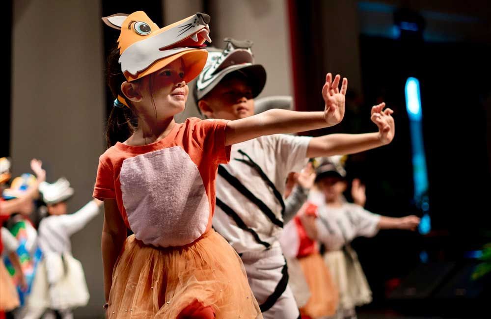 A group of children dressed in costumes are dancing on a stage.