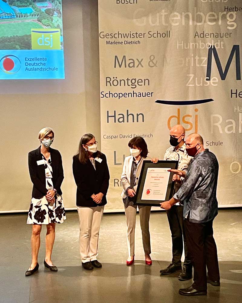 A group of people wearing face masks are standing in front of a wall that says gutenberg