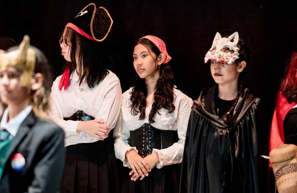 A group of children dressed in costumes are standing next to each other on a stage.