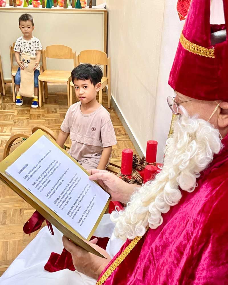 A man dressed as santa claus is reading a book to two children.