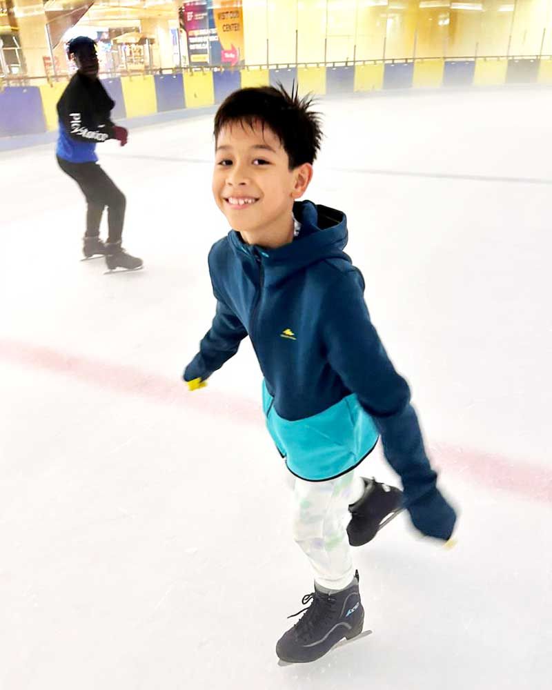 A young boy is ice skating on an indoor rink