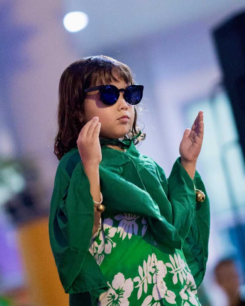 A little girl wearing sunglasses and a green dress