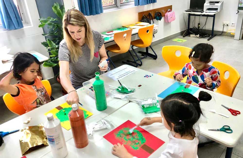 A group of children are sitting at a table making crafts.