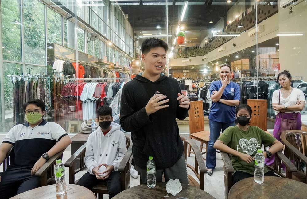 A man is standing in front of a group of people wearing masks.