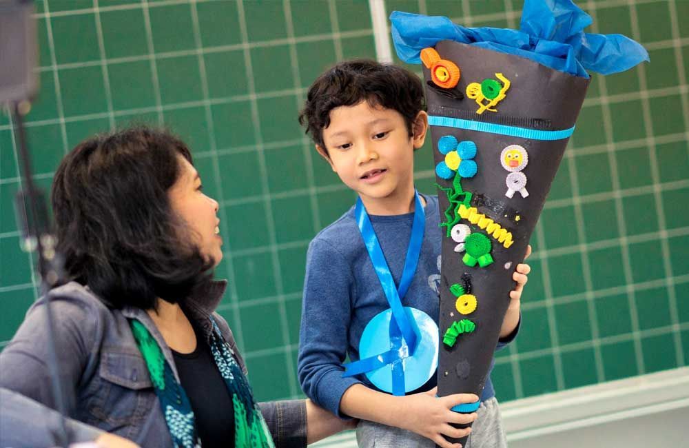 A woman is standing next to a young boy holding a cone.