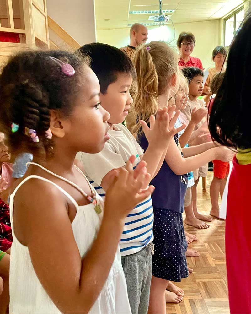 A group of children are clapping their hands in a room.