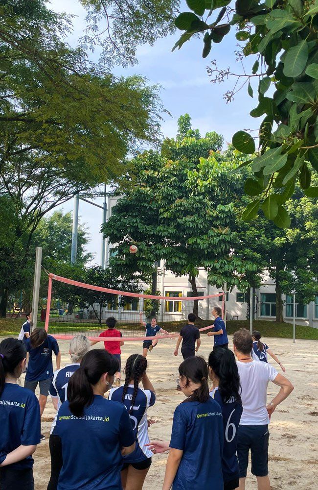 A group of people are playing volleyball in a park.
