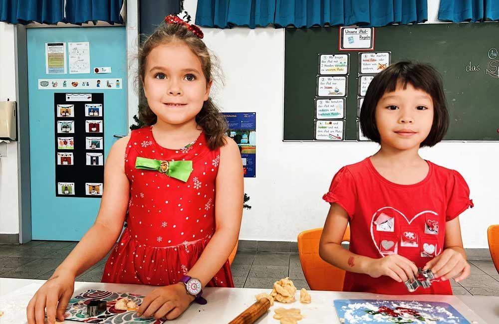 Two little girls are sitting at a table in a classroom