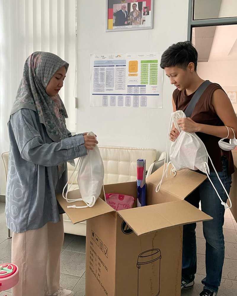 Two women are standing next to each other in front of a cardboard box.