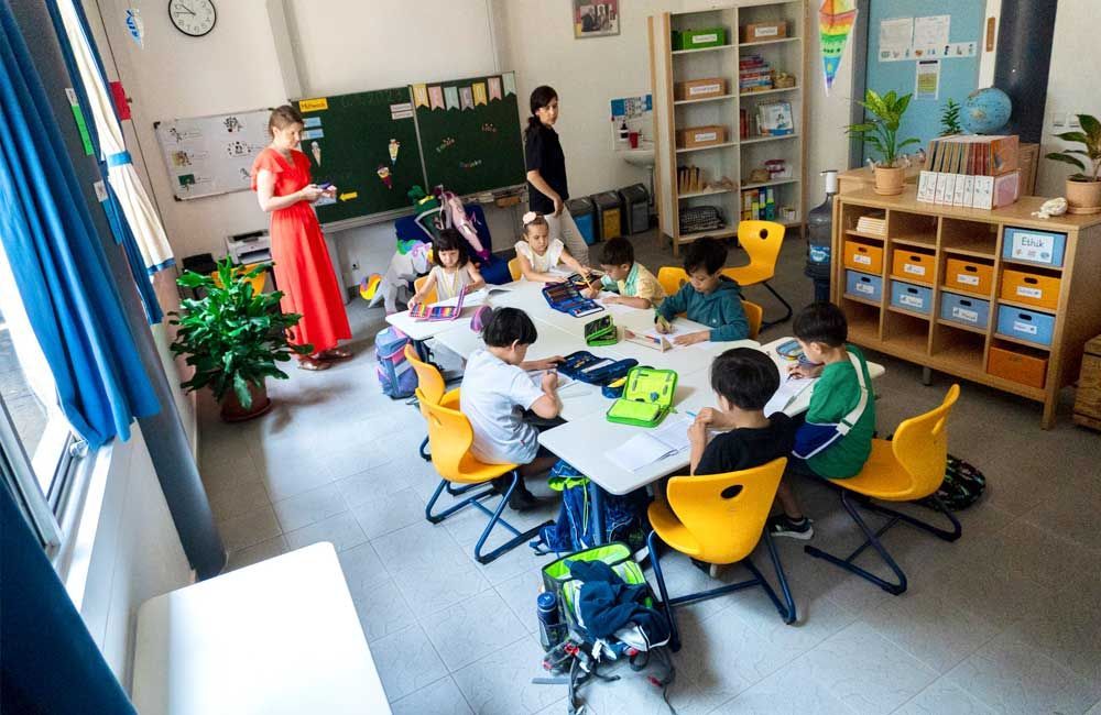 A group of children are sitting around a table in a classroom.