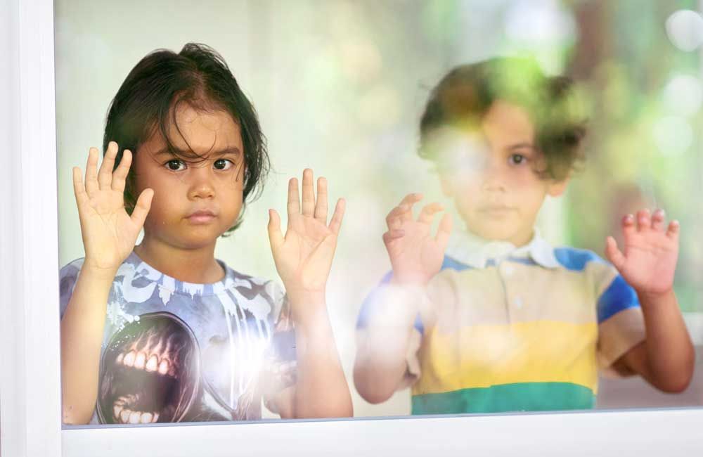 A boy and a girl are looking out of a window.