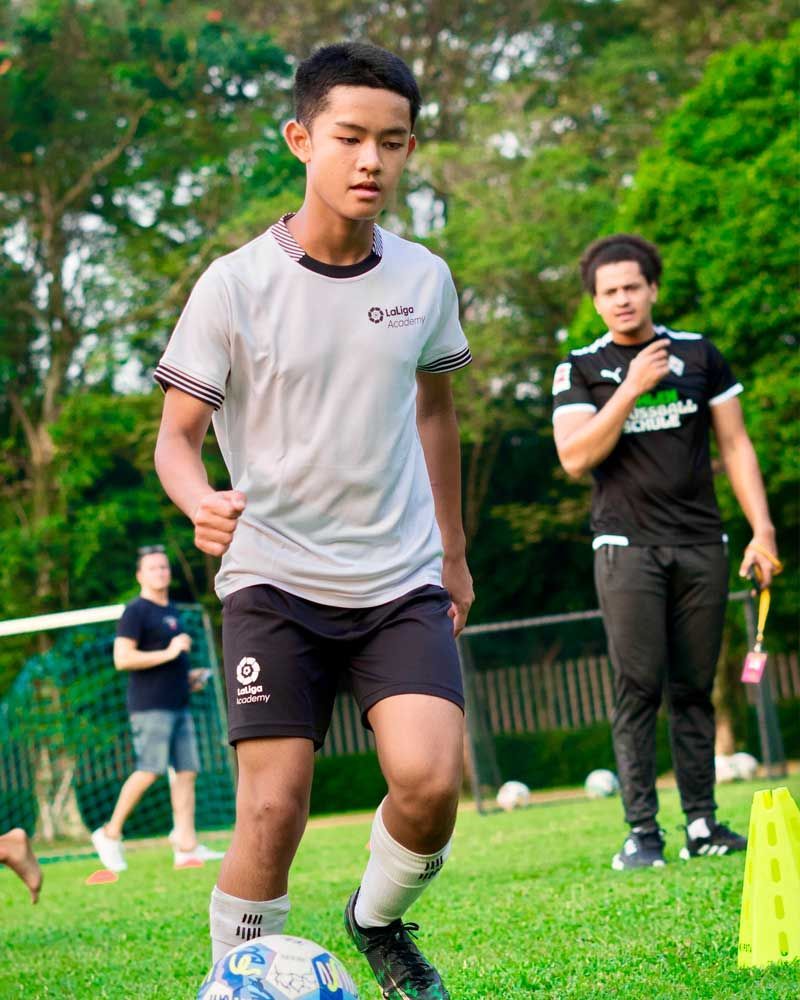 A young man is kicking a soccer ball on a field.