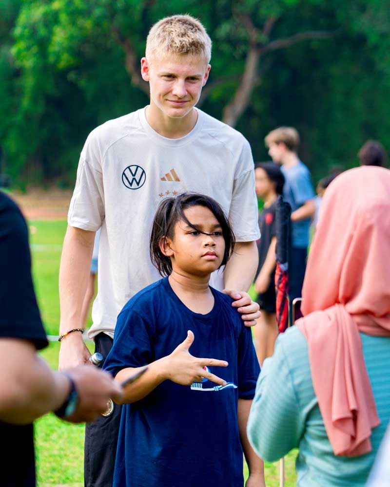A boy in a blue shirt is standing next to a man in a white shirt.