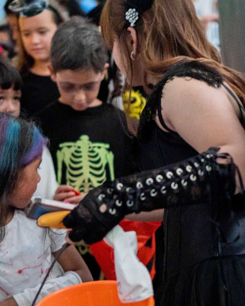 A woman in a black dress is standing in front of a group of children.