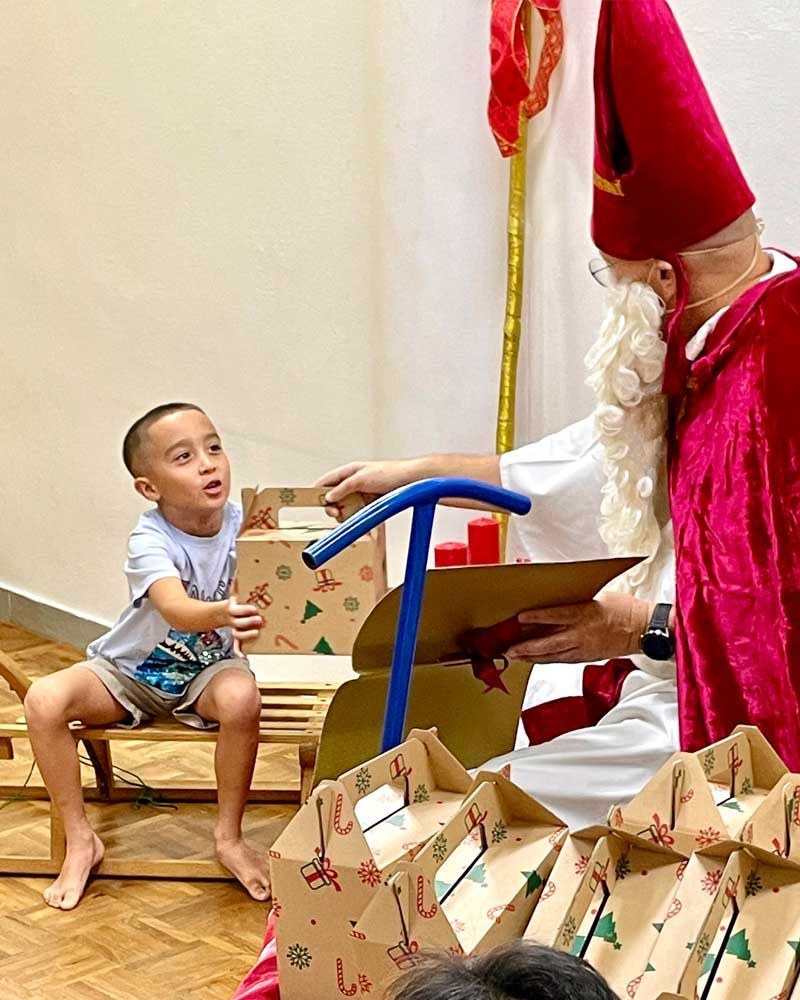 A little boy is sitting on a chair next to a man dressed as santa claus.