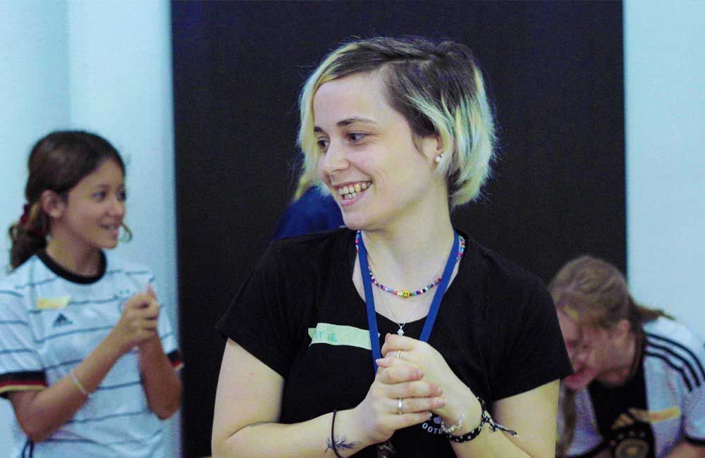 A woman in a black shirt with a lanyard around her neck is smiling