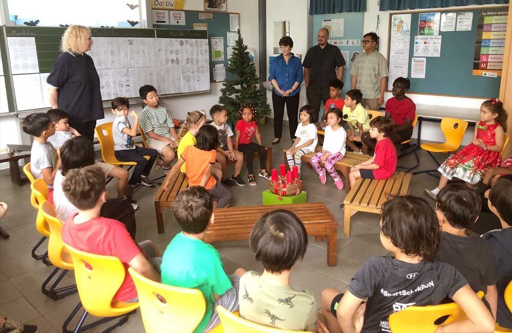 A group of children are sitting in a circle in front of a christmas tree.