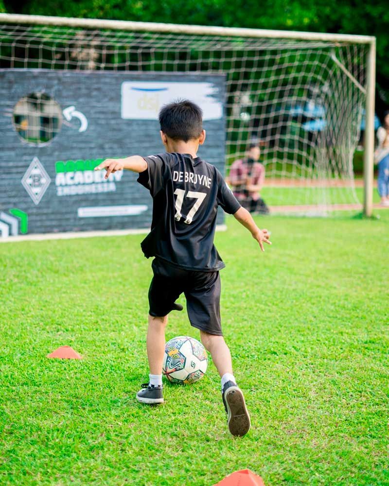 A young boy is kicking a soccer ball on a field.