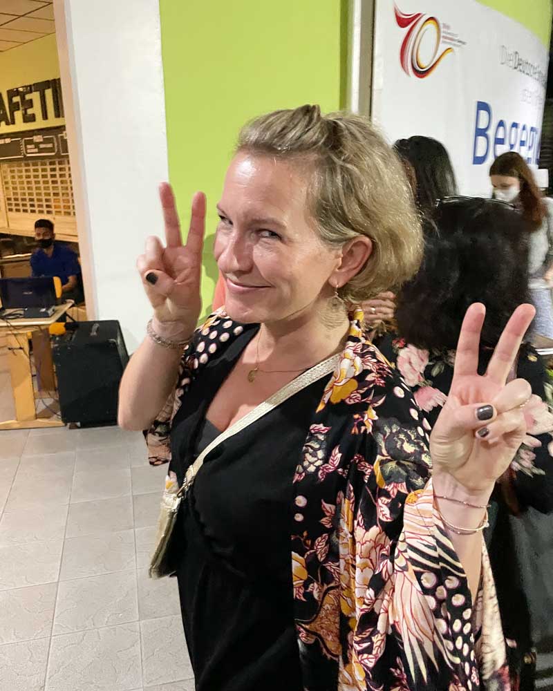 A woman in a black dress is giving a peace sign.