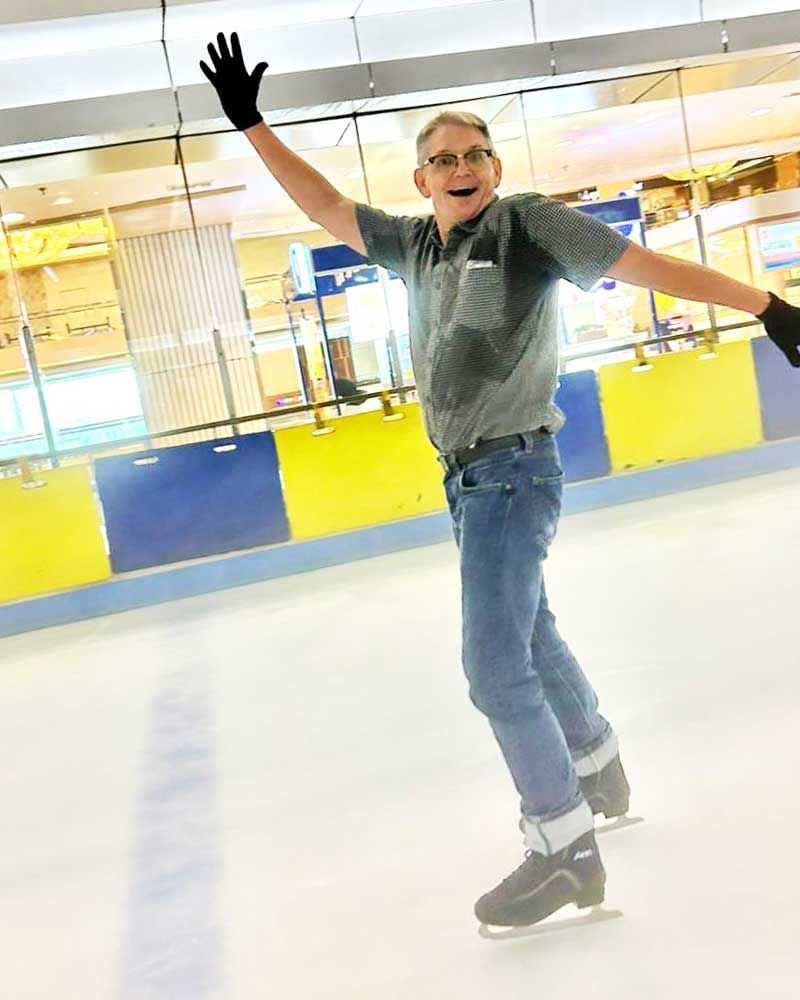 A man is ice skating with his arms outstretched
