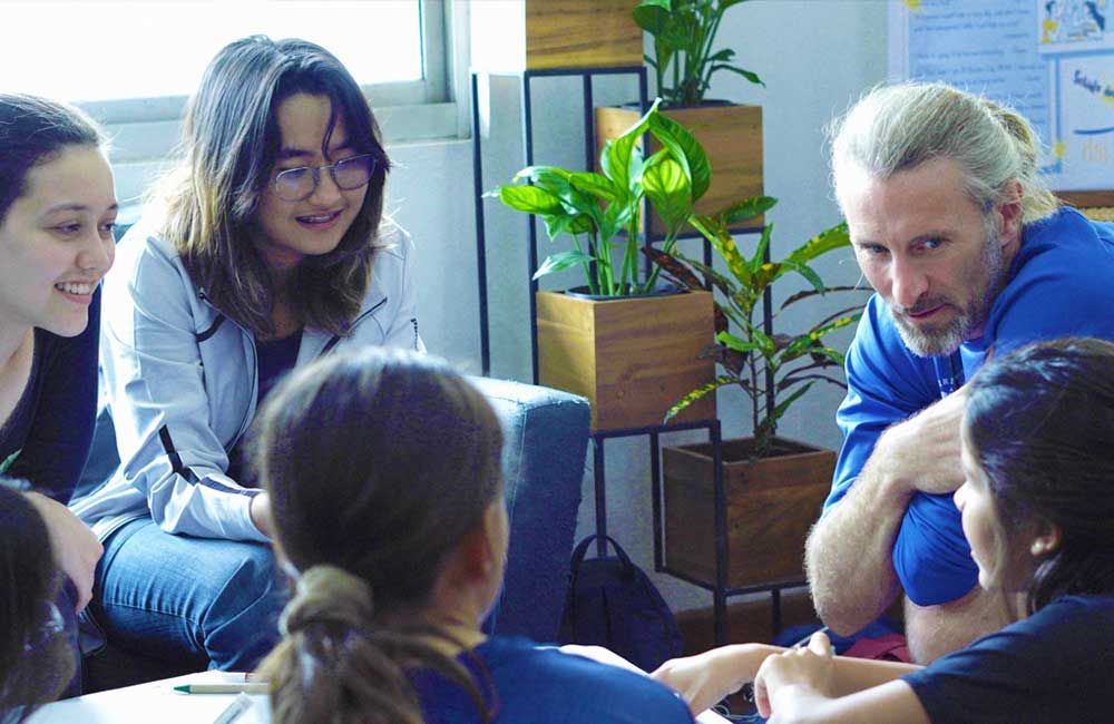 A group of people are sitting around a table talking to each other.