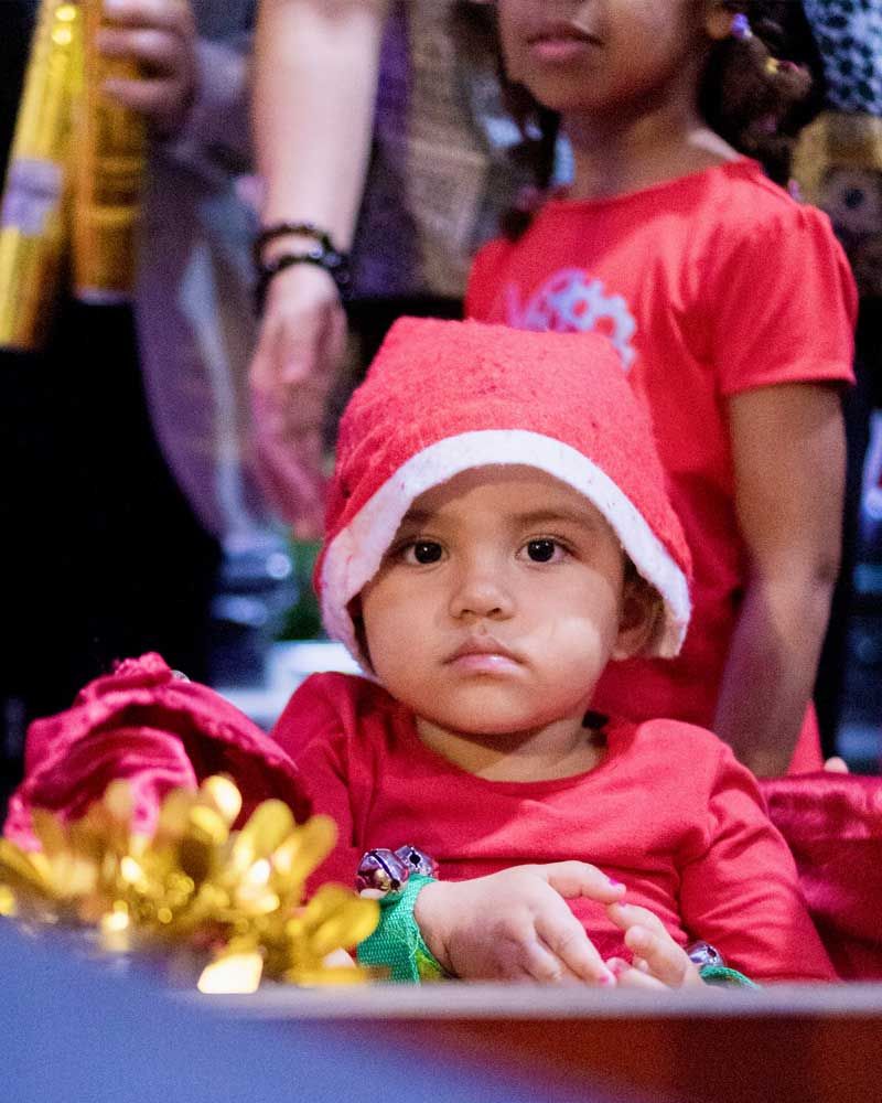 A baby wearing a santa hat and a red dress
