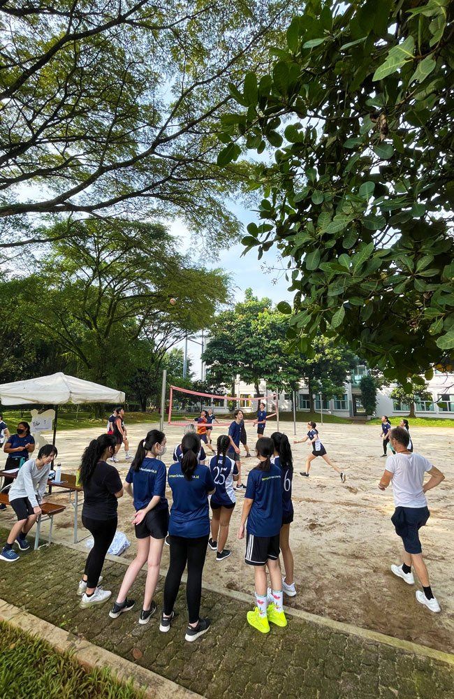 A group of young people are playing volleyball in a park.