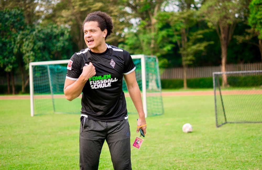 A man in a black shirt is standing on a soccer field.