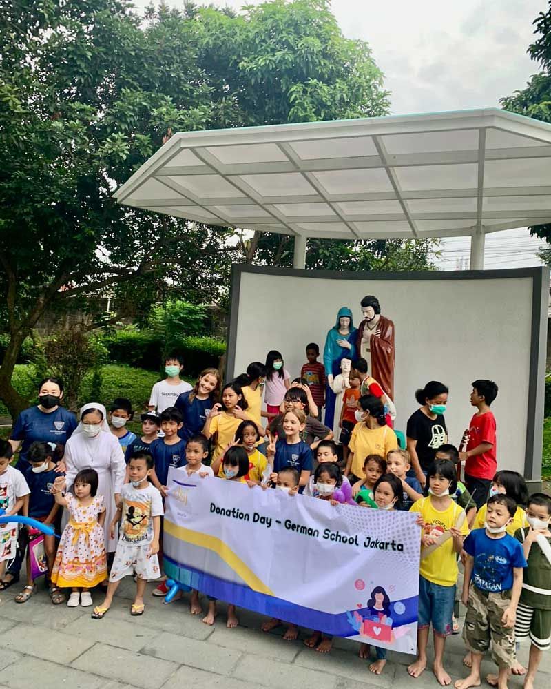 A group of children are standing in front of a stage holding a banner.