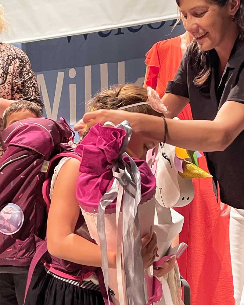 A woman is putting a unicorn costume on a little girl