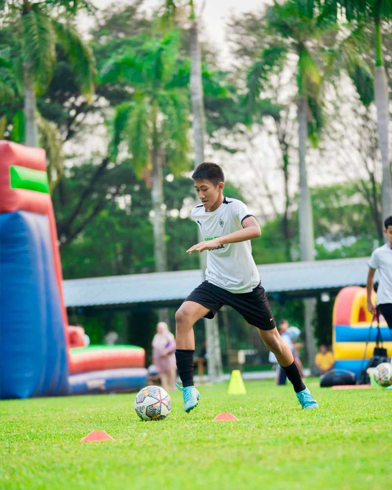 A young boy is kicking a soccer ball on a field.