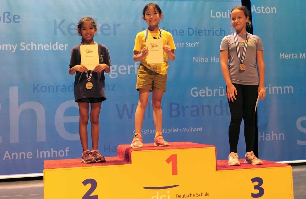 Three young girls are standing on a podium with numbers 1 2 and 3
