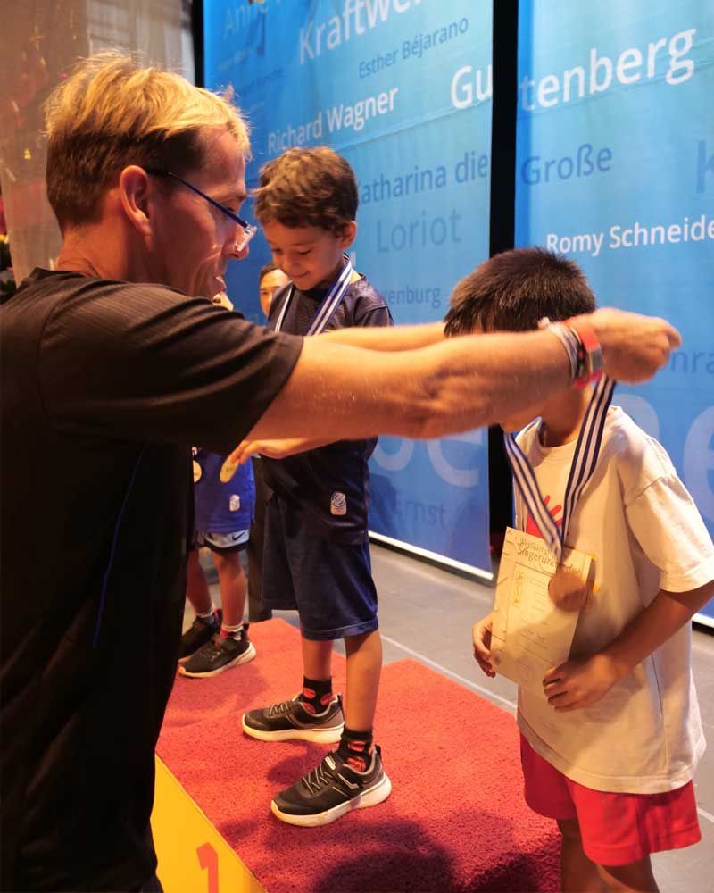 A man is giving a medal to a young boy