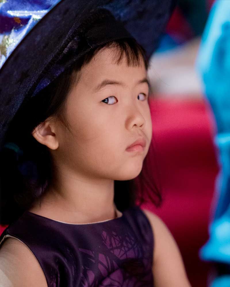 A little girl wearing a purple dress and a blue hat