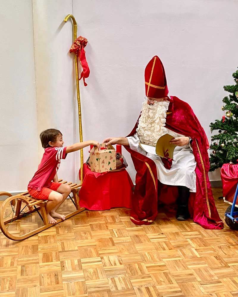 A little boy is giving a gift to santa claus
